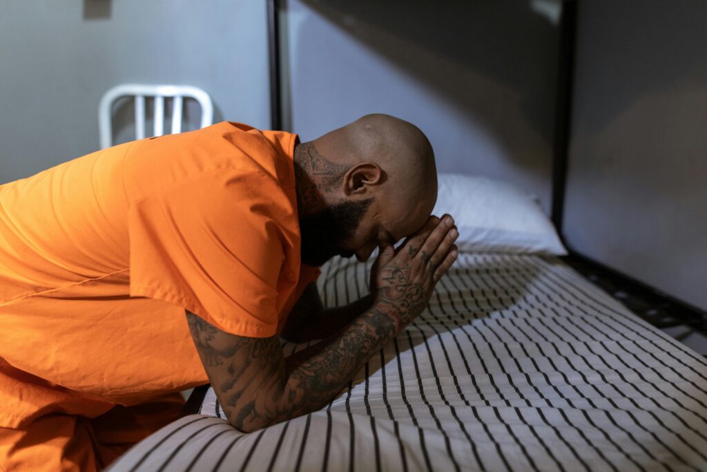 Man in Orange T-shirt Praying on Bed